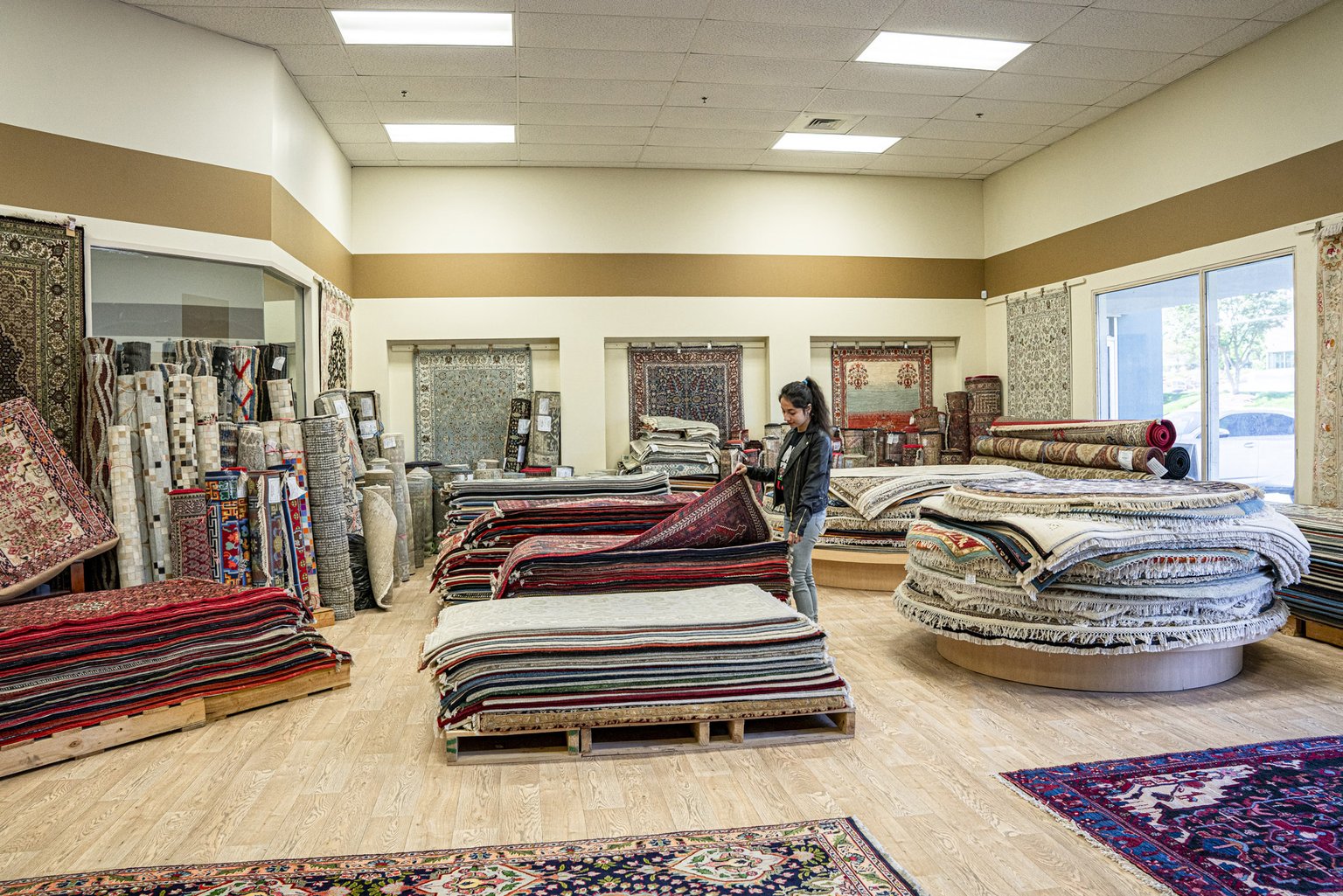 A Magic Rugs team member browsing stacks of rugs in the Charlotte showroom