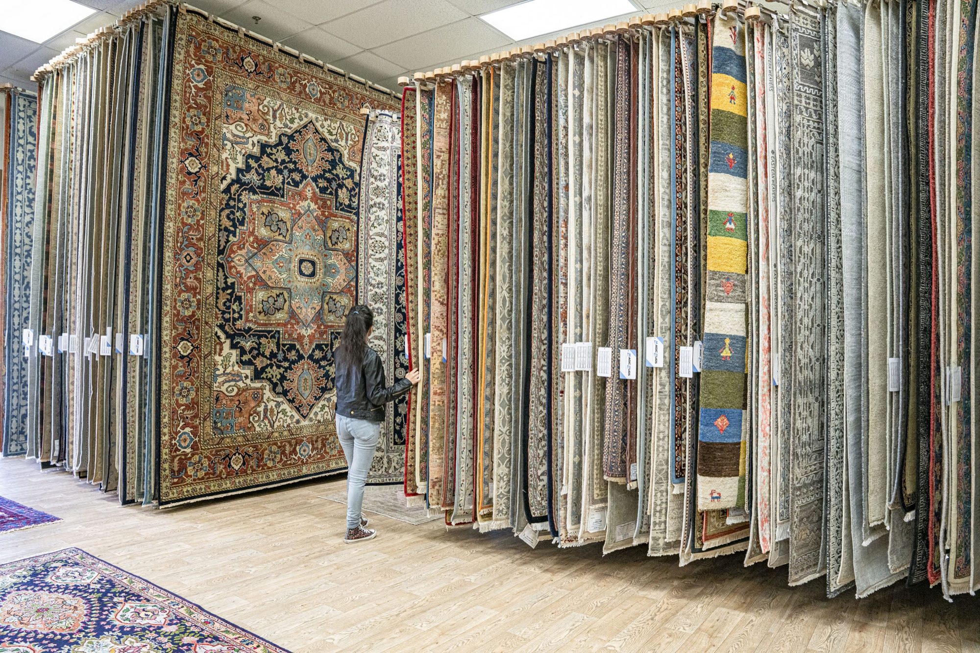 A customer browsing a wall of hanging rugs in the Charlotte showroom