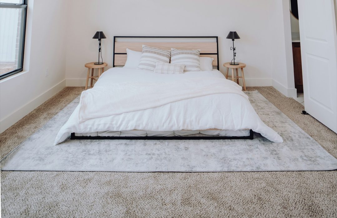 A bedroom with a large rug under the bed